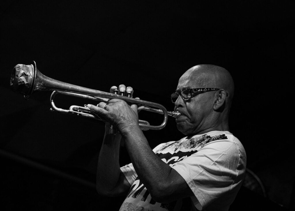 Trompetista con gafas tocando la trompeta en directo, en blanco y negro