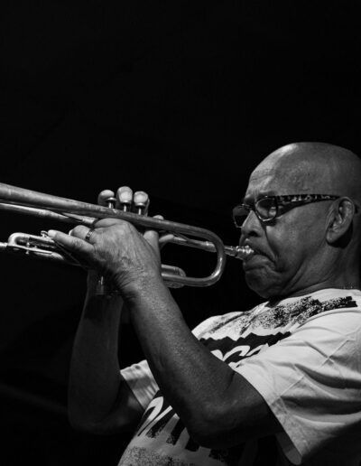 Trompetista con gafas tocando la trompeta en directo, en blanco y negro