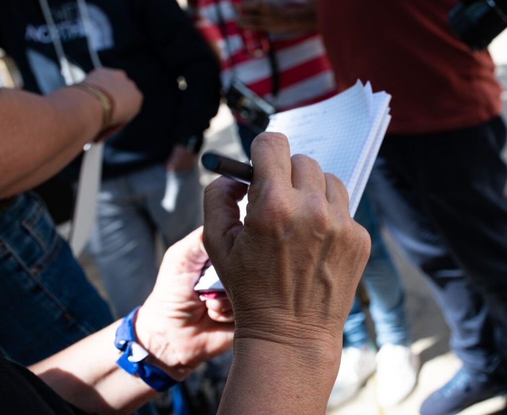 Detalle de unas manos sosteniendo unos papeles en un evento