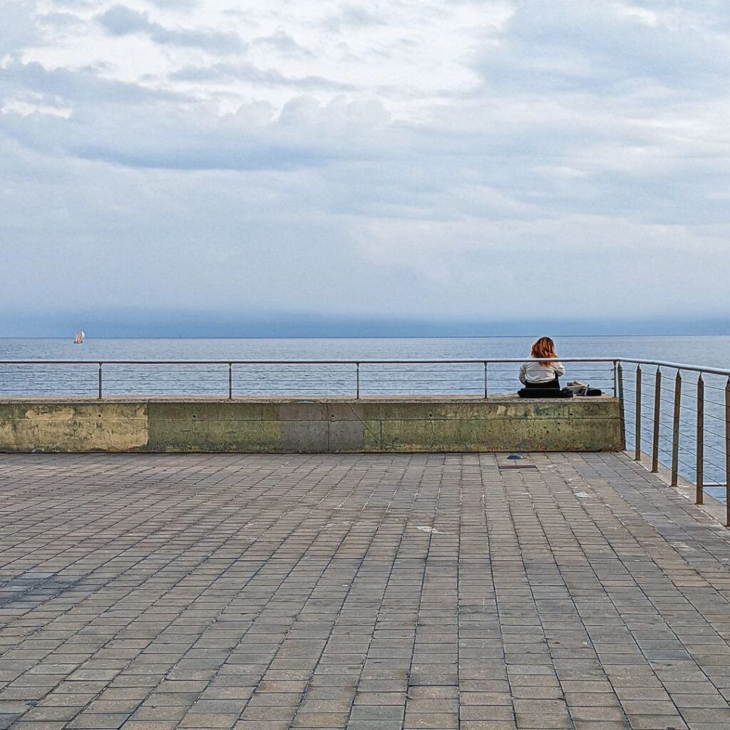 Persona sentada en un banco mirando al mar