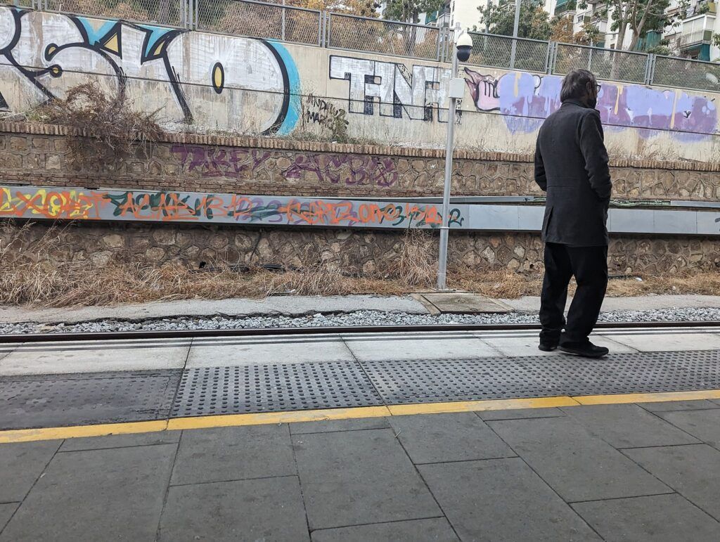 Persona caminando junto a un muro de grafiti en un andén