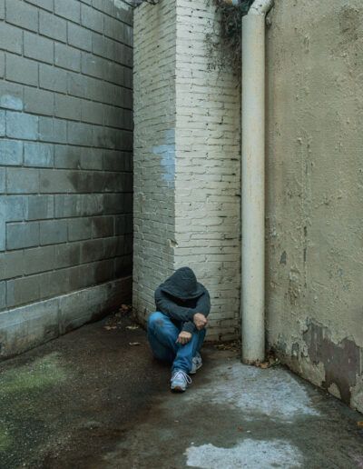 Autorretrato de un hombre agachado en un espacio de baldosas