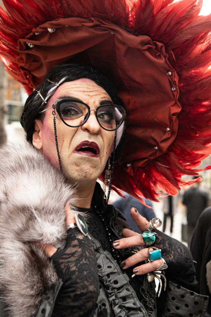 Persona con un elaborado sombrero de plumas rojas y gafas en una fiesta