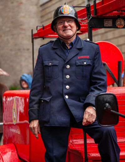 Hombre con uniforme de época junto a un autobús rojo