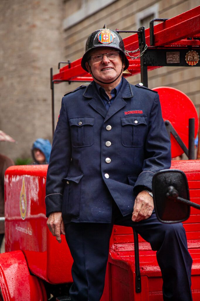 Hombre con uniforme de época junto a un autobús rojo