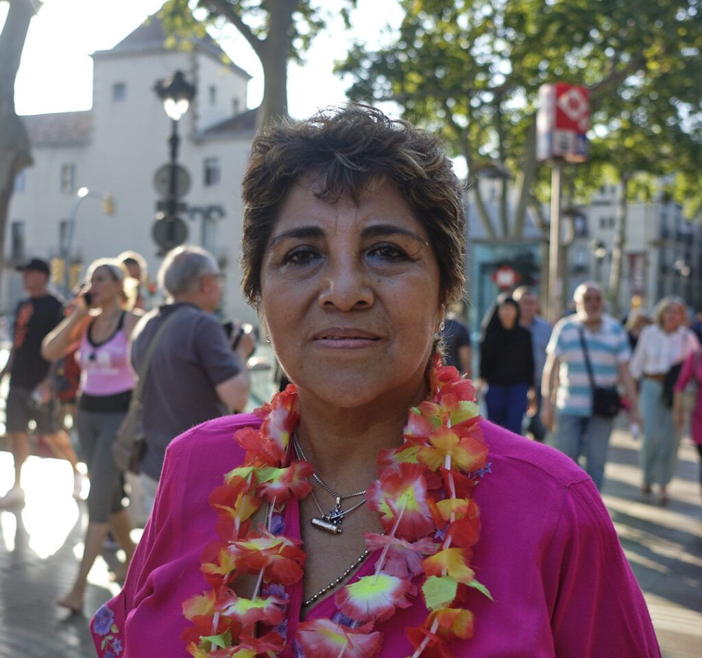 Mujer con collar de flores sonriendo en un evento al aire libre