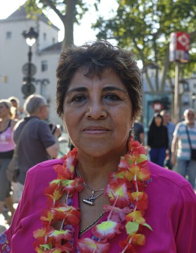 Mujer con collar de flores sonriendo en un evento al aire libre
