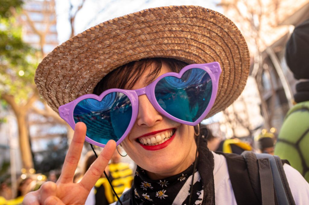 Joven con gafas de sol en forma de corazón y sombrero de paja sonriendo