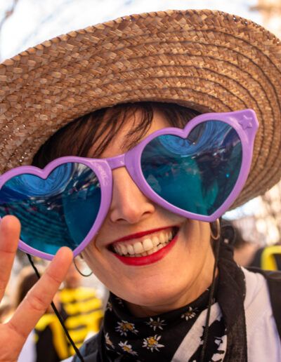 Joven con gafas de sol en forma de corazón y sombrero de paja sonriendo