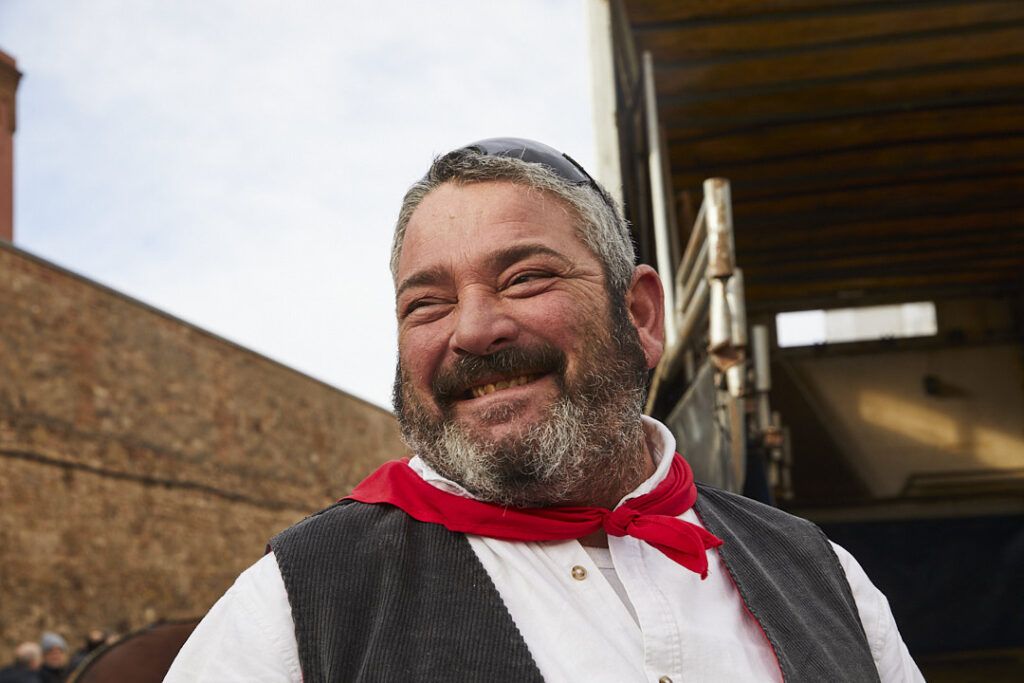 Hombre con barba y pañuelo rojo sonriendo en una fiesta popular