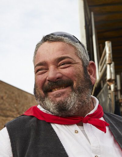 Hombre con barba y pañuelo rojo sonriendo en una fiesta popular