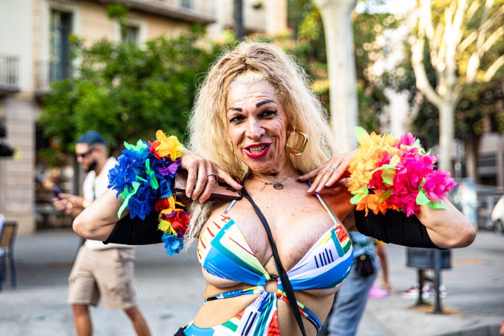 Persona con vestido colorido y flores celebrando en el desfile del Orgullo