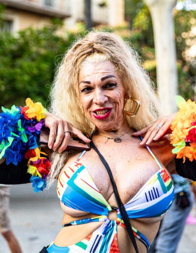 Persona con vestido colorido y flores celebrando en el desfile del Orgullo