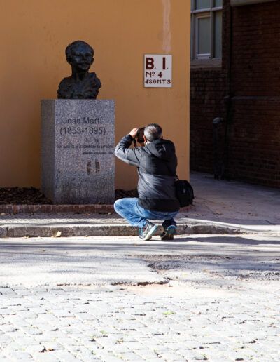 Persona agachada fotografiando cerca de una escultura