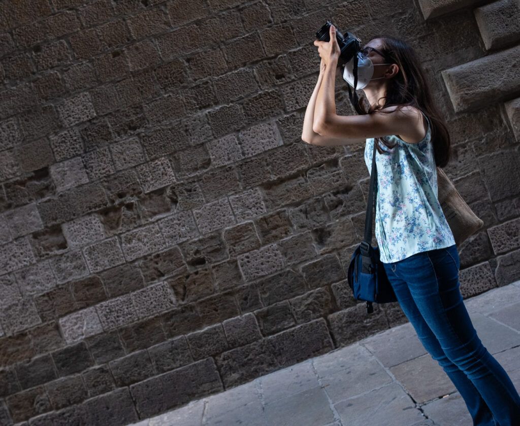 Mujer joven fotografiando ante un muro de piedra