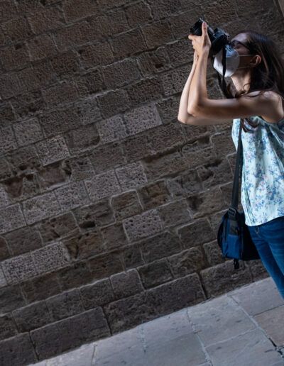 Mujer joven fotografiando ante un muro de piedra