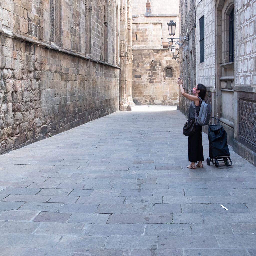 Dos personas con equipaje caminando por un callejón de Barcelona