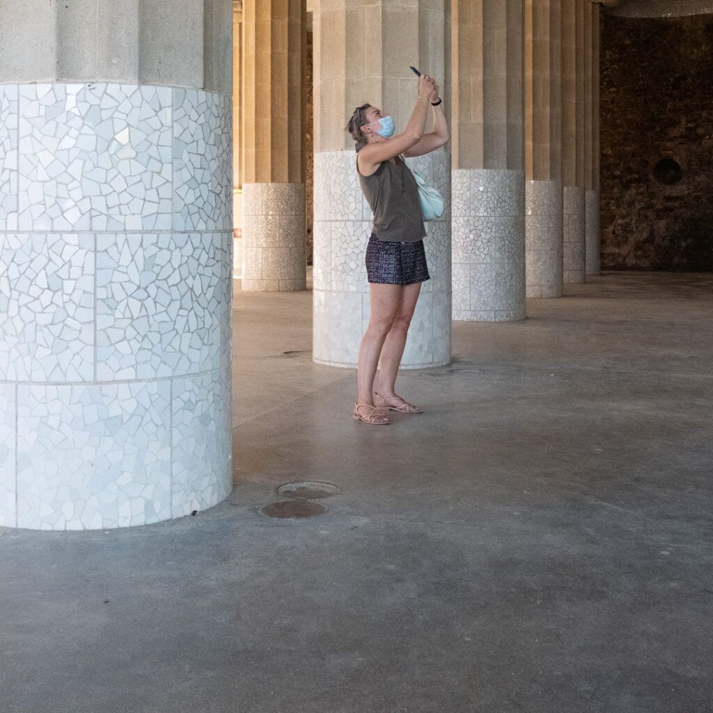 Persona fotografiando junto a una columna bajo una columnata