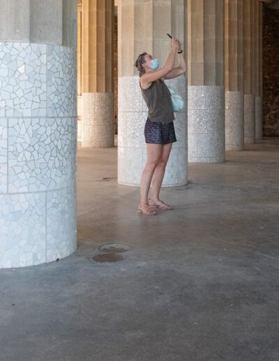 Persona fotografiando junto a una columna bajo una columnata