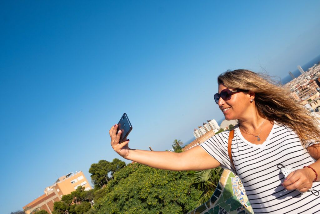 Mujer con gafas de sol tomando un selfi con el móvil al aire libre