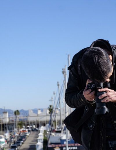 Persona fotografiando en un puerto deportivo bajo el cielo azul
