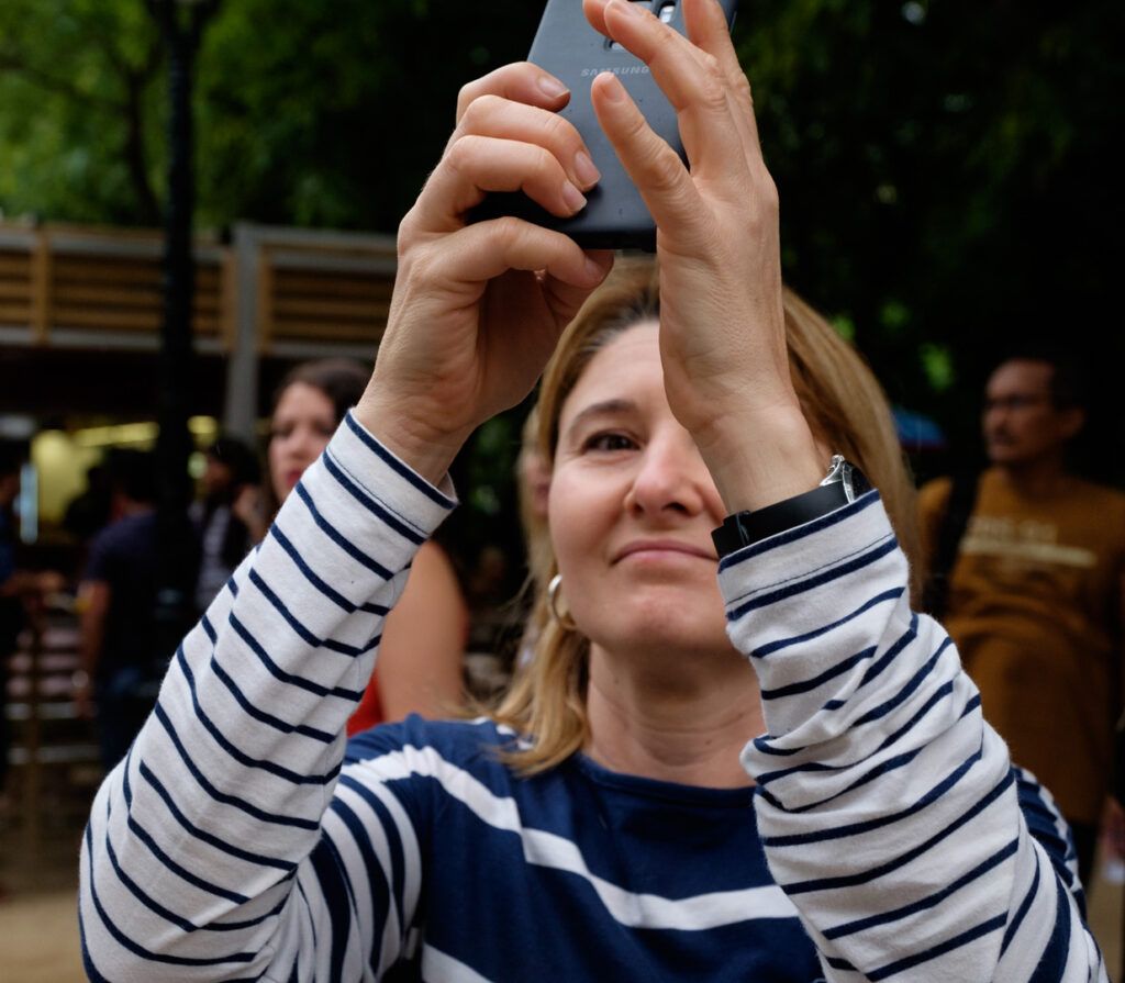 Mujer con jersey de rayas tomando una foto con el teléfono móvil