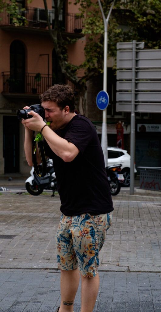 Hombre con pantalón corto fotografiando en una plaza