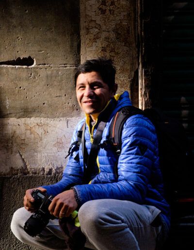 Hombre con chaqueta azul agachado tomando una foto con el móvil