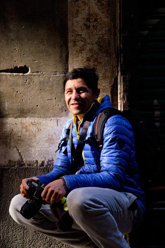 Hombre con chaqueta azul agachado tomando una foto con el móvil