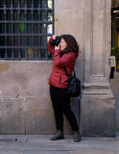 Persona con chaqueta roja fotografiando junto a un edificio