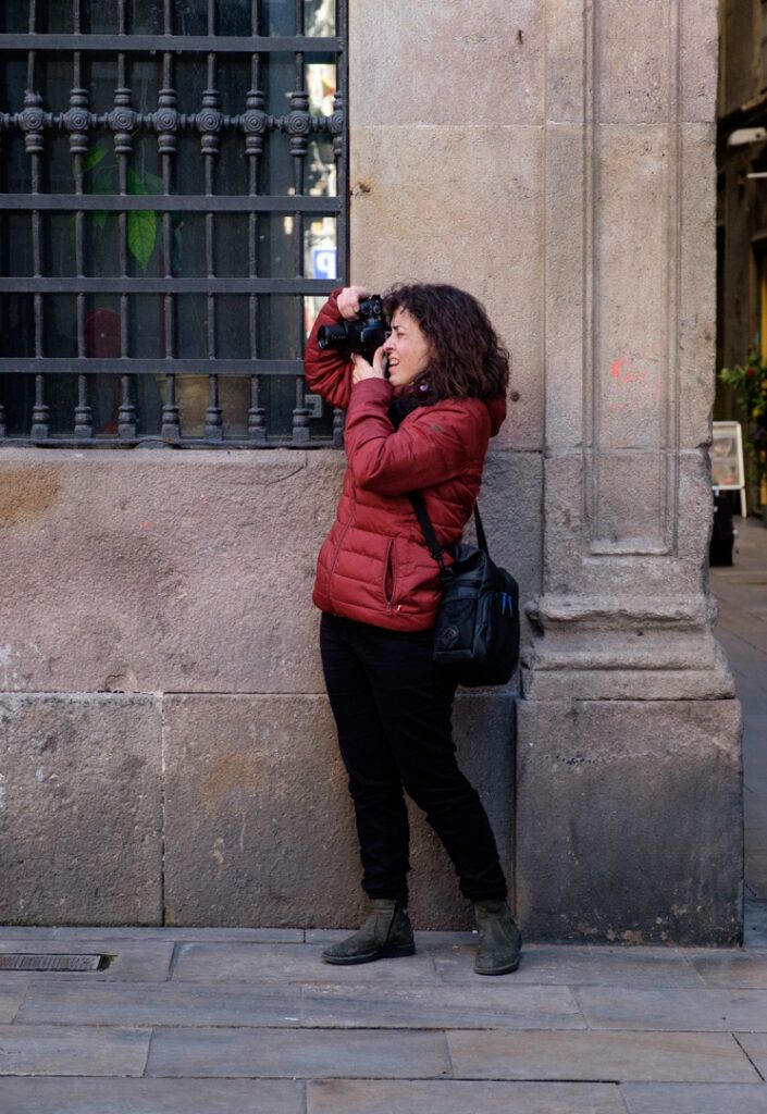 Persona con chaqueta roja fotografiando junto a un edificio