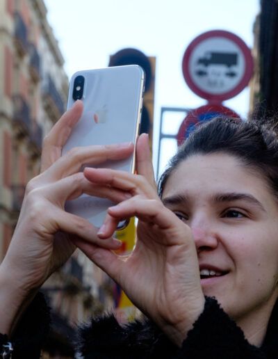 Mujer joven tomando una foto con el teléfono móvil en la calle