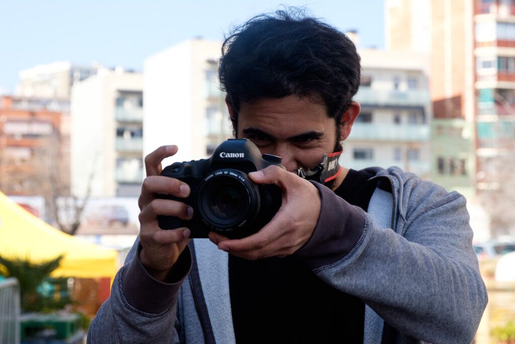 Hombre joven fotografiando con una cámara réflex en un mercado