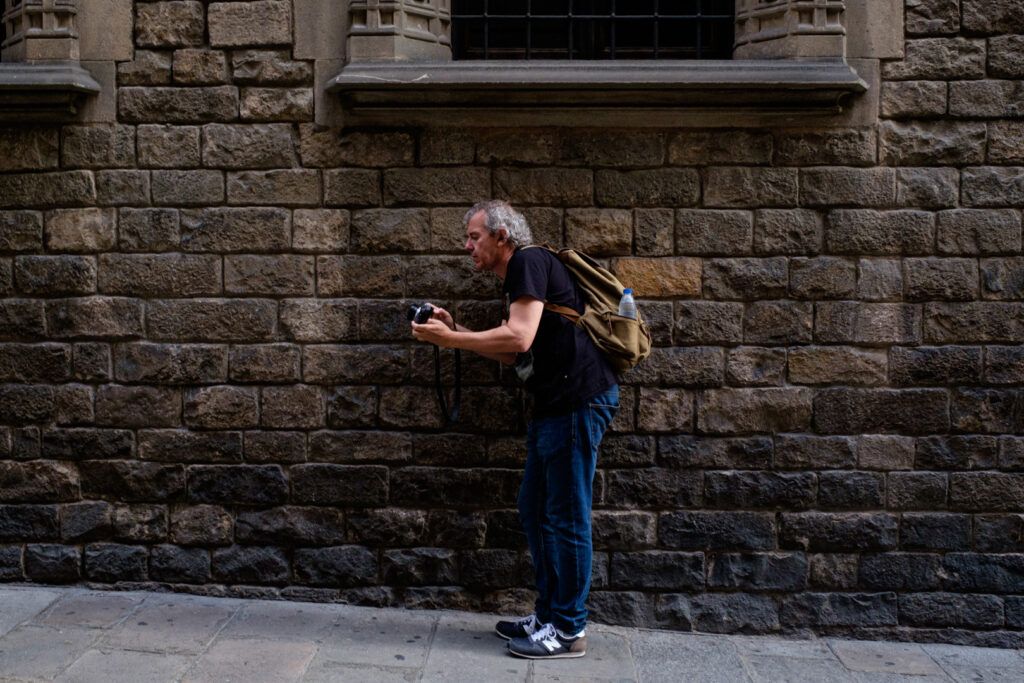 Hombre fotografiando ante un muro de ladrillo en la calle