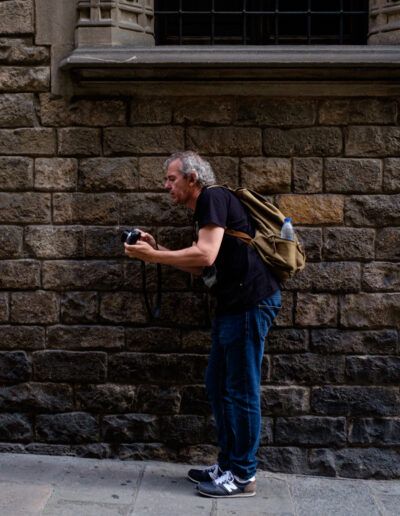 Hombre fotografiando ante un muro de ladrillo en la calle