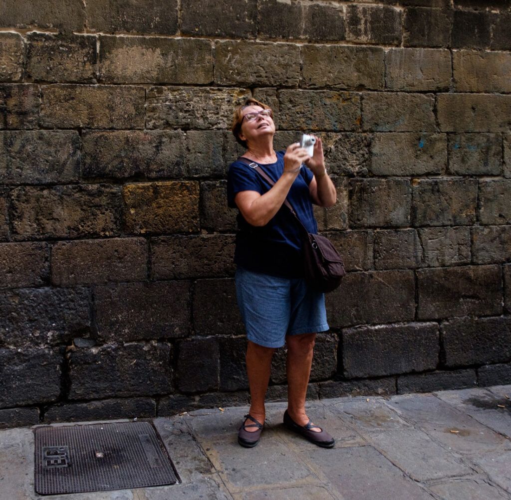 Mujer fotografiando con su teléfono móvil ante un muro de piedra