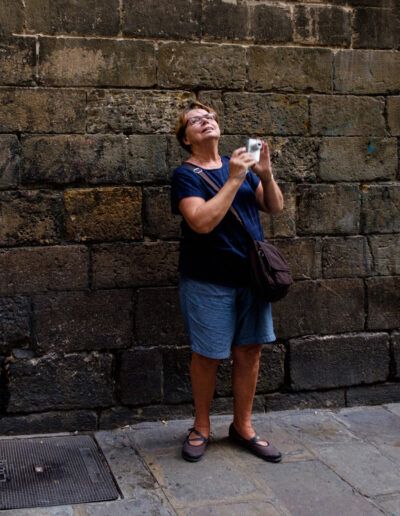 Mujer fotografiando con su teléfono móvil ante un muro de piedra