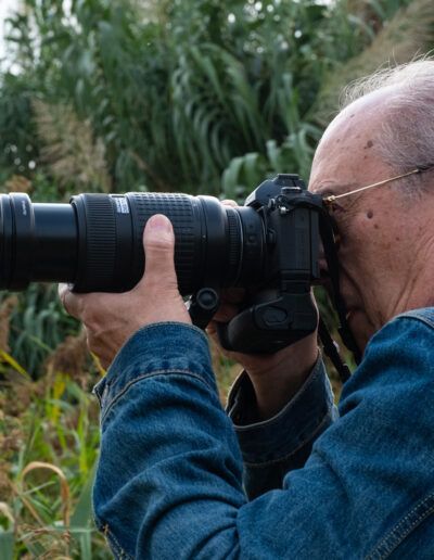 Hombre de cabello blanco fotografiando con un gran teleobjetivo