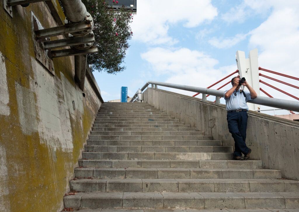 Persona fotografiando en unas escaleras urbanas bajo el cielo azul