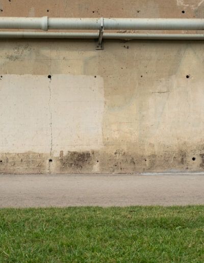 Fotógrafo de pequeño tamaño disparando ante un gran muro de hormigón