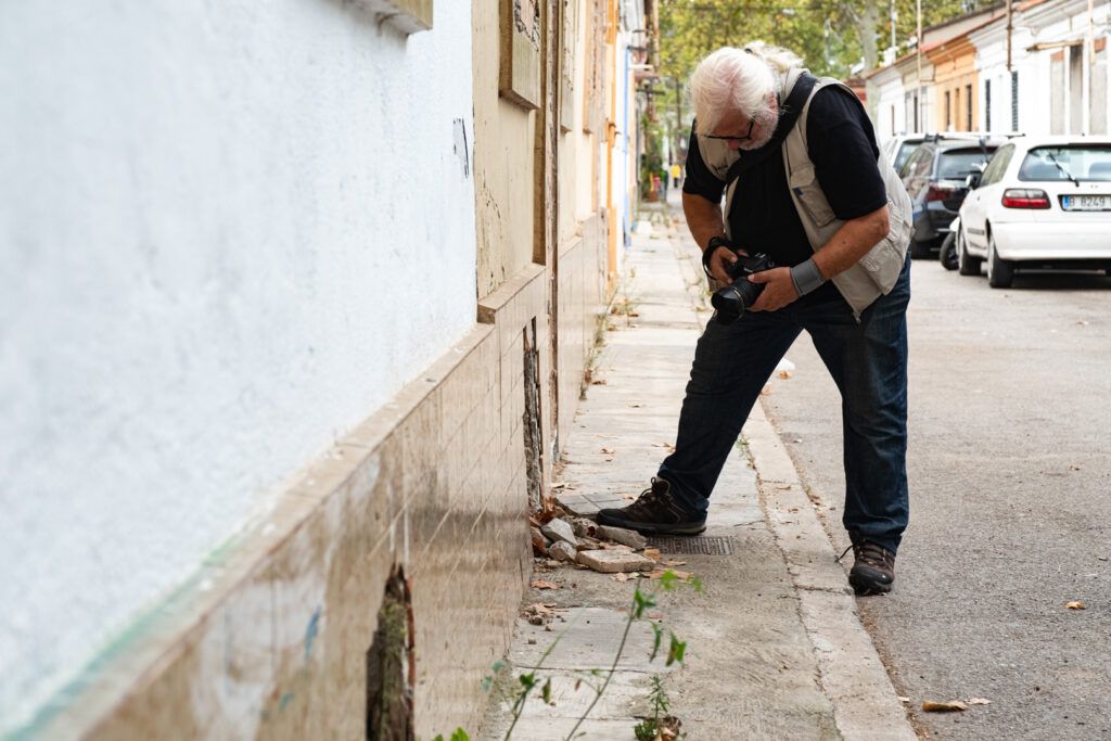 Hombre mayor inclinado fotografiando en una calle de Barcelona