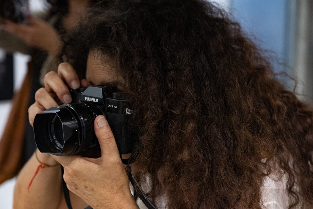 Mujer de cabello rizado fotografiando con una cámara réflex