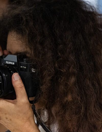 Mujer de cabello rizado fotografiando con una cámara réflex