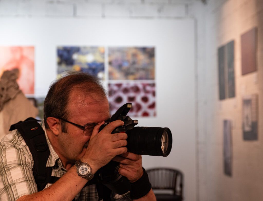 Hombre con gafas fotografiando con una cámara réflex en una galería