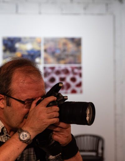 Hombre con gafas fotografiando con una cámara réflex en una galería