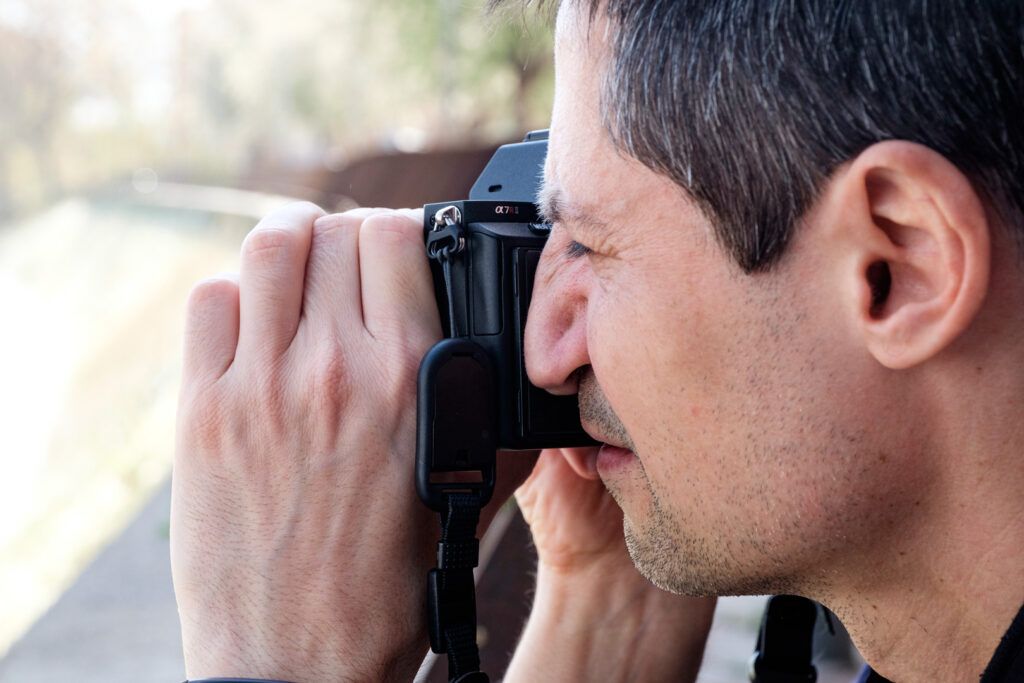 Hombre de perfil fotografiando con su cámara réflex