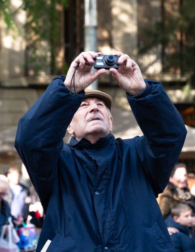 Hombre fotografiando hacia arriba con su cámara en la calle