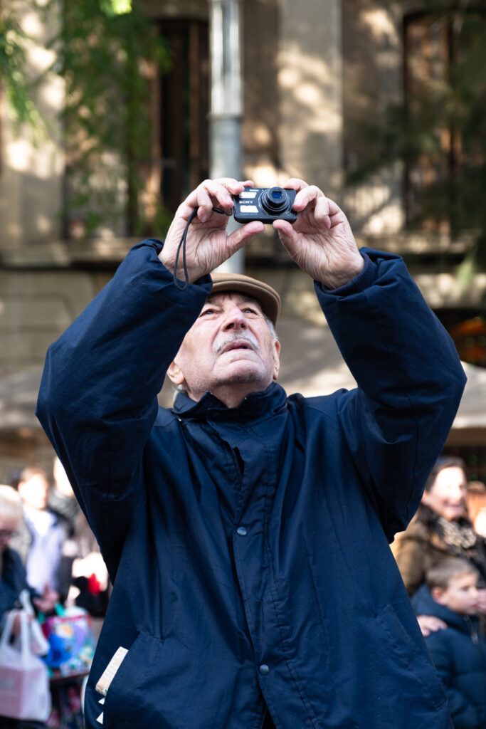 Hombre fotografiando hacia arriba con su cámara en la calle