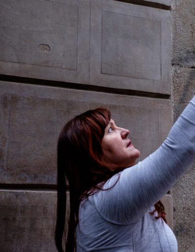Mujer con el brazo en alto fotografiando con el móvil junto a un muro