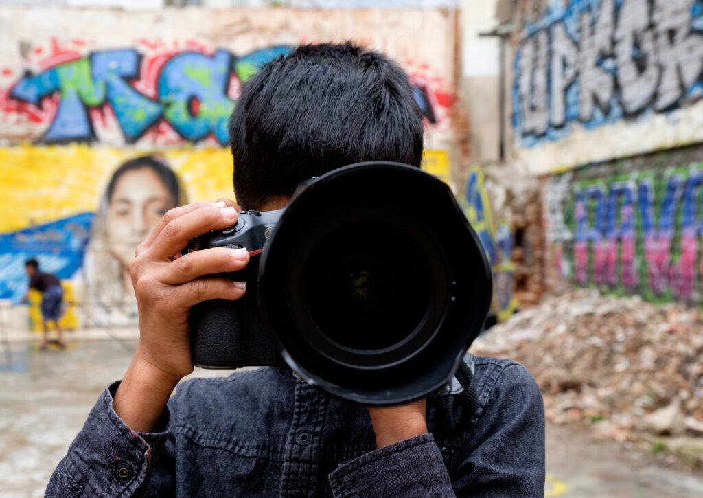 Fotógrafo disparando con un teleobjetivo ante una pared con grafiti